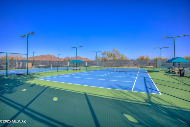 view of tennis court featuring community basketball court and fence