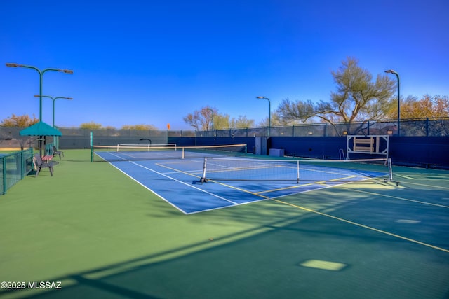 view of tennis court with community basketball court and fence