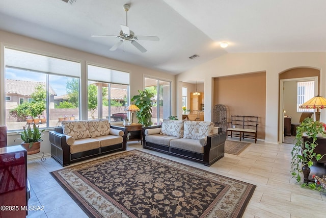 living room with lofted ceiling, arched walkways, ceiling fan with notable chandelier, visible vents, and baseboards