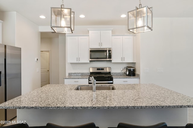 kitchen featuring light stone countertops, a kitchen island with sink, appliances with stainless steel finishes, and a breakfast bar