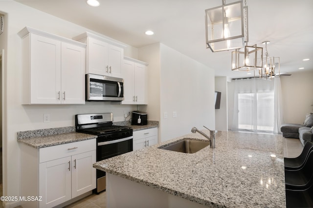 kitchen featuring light stone countertops, white cabinetry, stainless steel appliances, and a sink