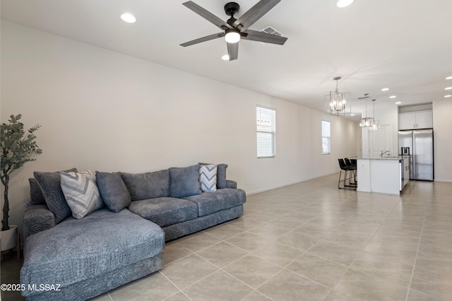 living room with light tile patterned floors, recessed lighting, visible vents, and ceiling fan with notable chandelier