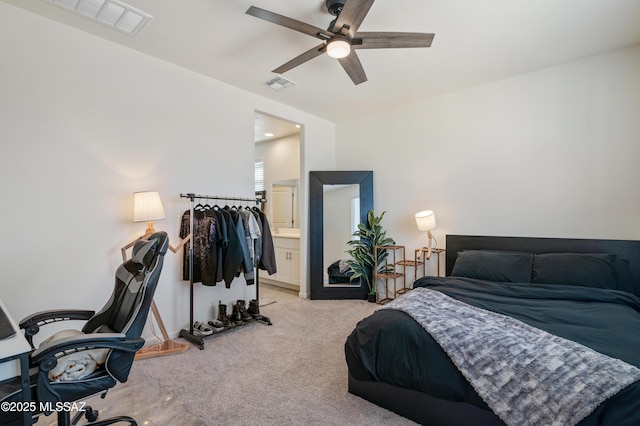 bedroom featuring a ceiling fan, ensuite bath, visible vents, and light colored carpet