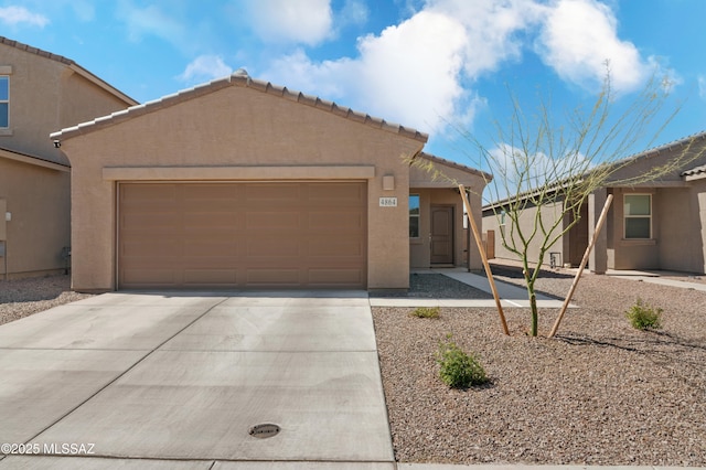 view of front of home featuring a garage, concrete driveway, a tiled roof, and stucco siding