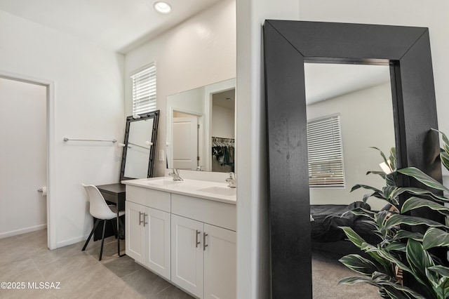 bathroom featuring double vanity, tile patterned flooring, a sink, and baseboards