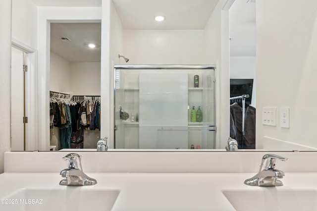 full bath with a stall shower, a spacious closet, and a sink