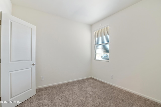 empty room featuring carpet and baseboards