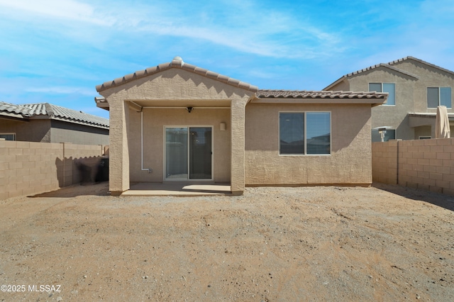 rear view of house with a tiled roof, a patio area, a fenced backyard, and stucco siding