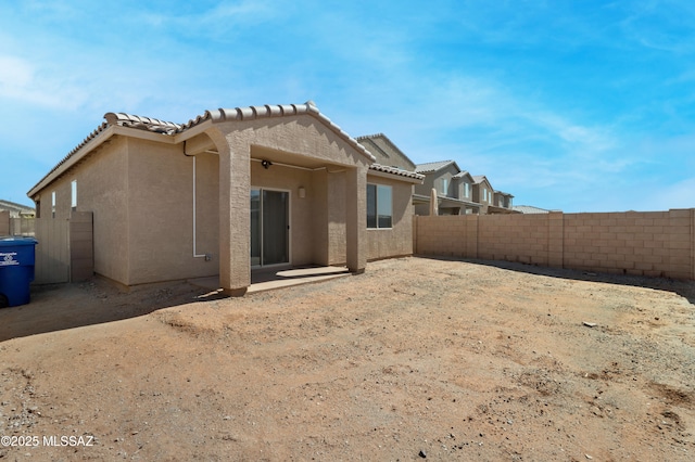 rear view of property with a tiled roof, fence, a patio, and stucco siding