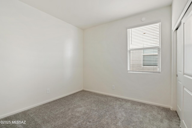 spare room featuring carpet and baseboards