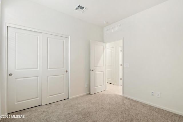 unfurnished bedroom with a closet, carpet, visible vents, and baseboards