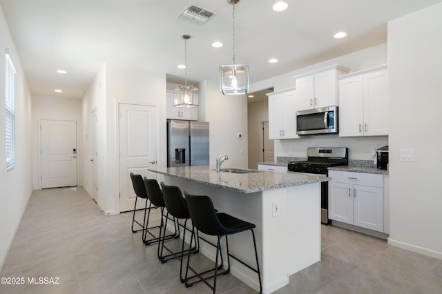 kitchen with a breakfast bar area, recessed lighting, a sink, appliances with stainless steel finishes, and an island with sink