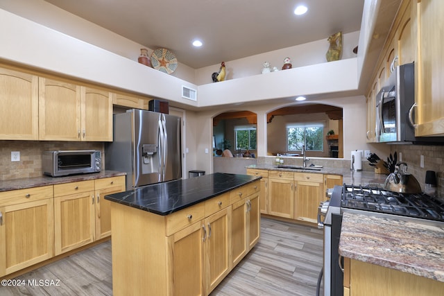 kitchen with stainless steel appliances, light brown cabinets, a sink, and visible vents