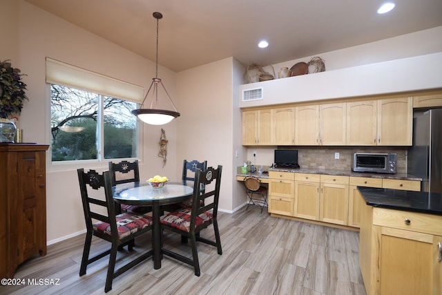 kitchen featuring light brown cabinetry, freestanding refrigerator, built in study area, and visible vents