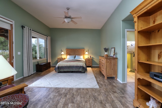 bedroom with baseboards, ensuite bath, wood finished floors, and access to exterior