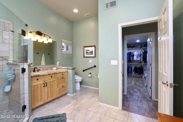 bathroom with toilet, vanity, a shower stall, and visible vents