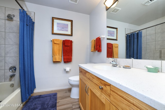 full bath featuring toilet, vanity, wood finished floors, and visible vents