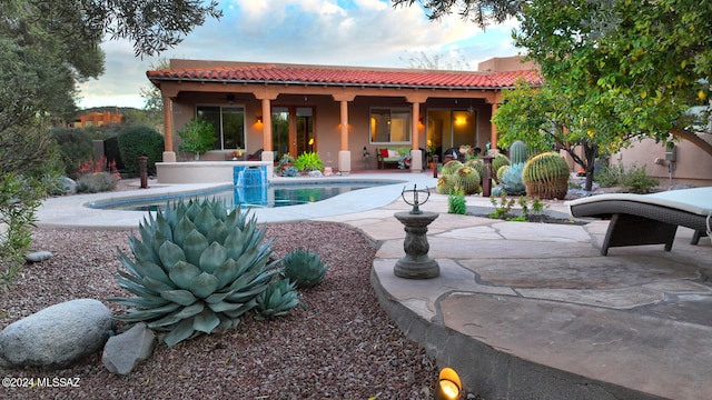 rear view of house featuring a patio area, stucco siding, an outdoor pool, and a tiled roof