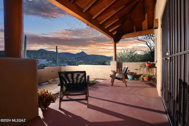 patio terrace at dusk featuring a mountain view and fence