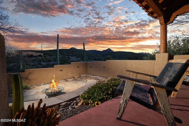 view of patio / terrace with a fire pit, fence, and a mountain view