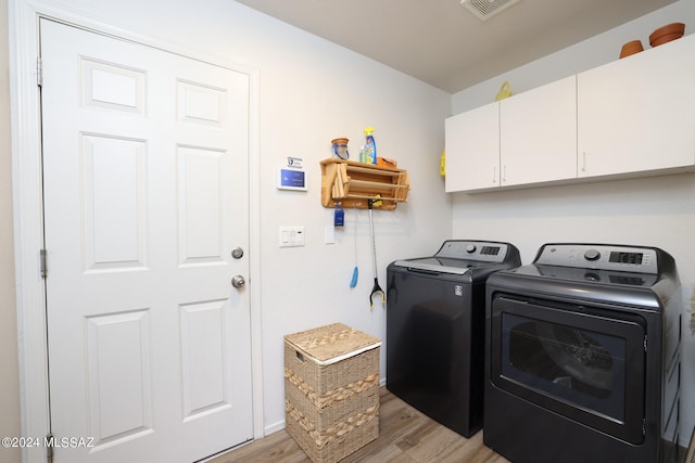 laundry area with washer and dryer, visible vents, cabinet space, and light wood-style flooring