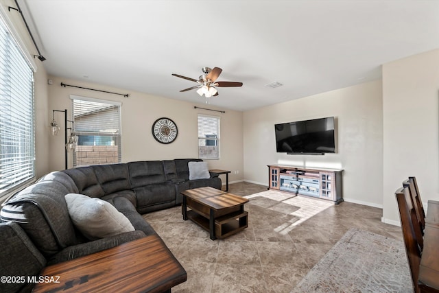 living area with visible vents, a ceiling fan, and baseboards