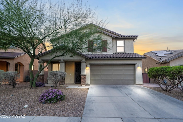 view of front of house featuring stucco siding, concrete driveway, an attached garage, and a tiled roof