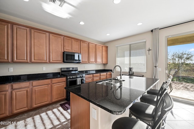 kitchen with visible vents, a sink, appliances with stainless steel finishes, a breakfast bar area, and light tile patterned floors