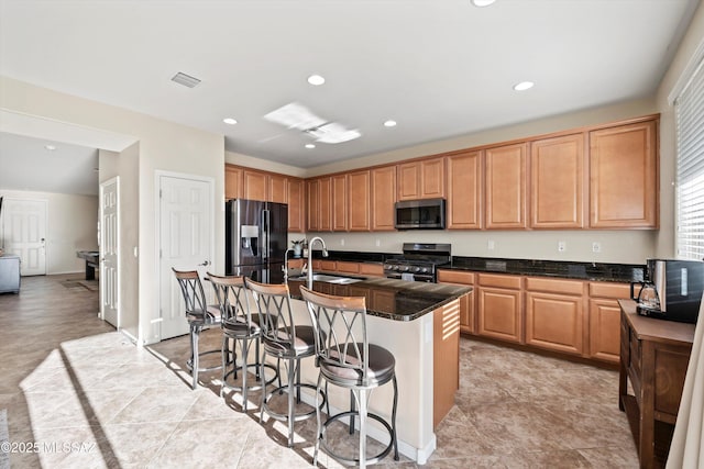 kitchen with an island with sink, a sink, a kitchen breakfast bar, recessed lighting, and stainless steel appliances