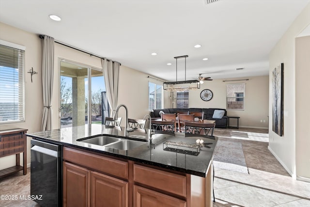 kitchen with dark stone countertops, an island with sink, recessed lighting, a sink, and open floor plan