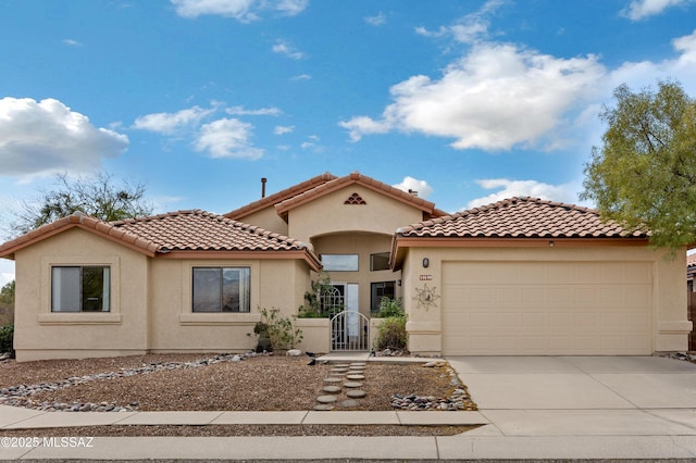 mediterranean / spanish-style home featuring an attached garage, driveway, a tile roof, and stucco siding