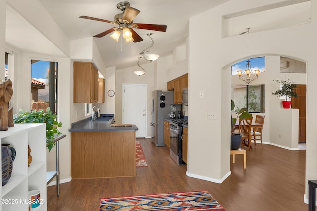 kitchen featuring stainless steel appliances, dark countertops, dark wood finished floors, and a sink