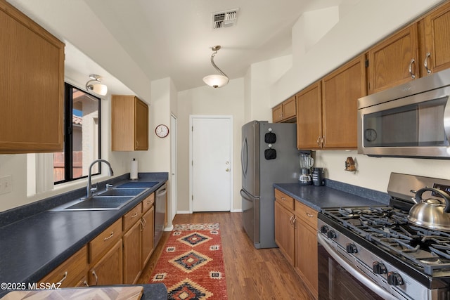 kitchen featuring dark countertops, visible vents, stainless steel appliances, and a sink