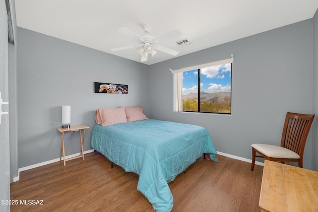 bedroom featuring a ceiling fan, baseboards, visible vents, and wood finished floors