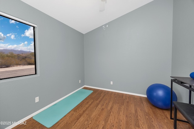 exercise area with vaulted ceiling, baseboards, and wood finished floors