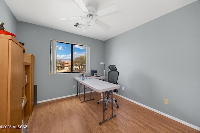 office area with light wood finished floors, baseboards, visible vents, and a ceiling fan