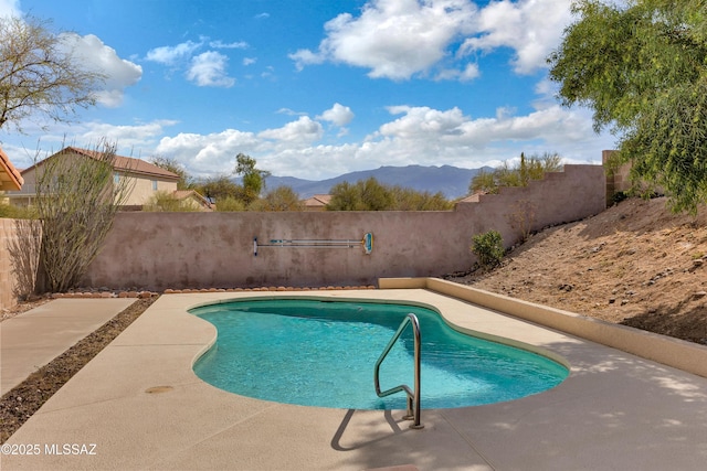 view of pool featuring a patio area, a fenced backyard, a mountain view, and a fenced in pool