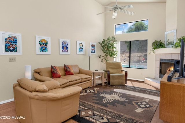 living room featuring ceiling fan, a fireplace, wood finished floors, and baseboards