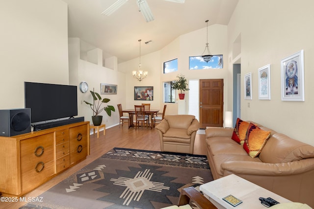 living room featuring ceiling fan with notable chandelier, high vaulted ceiling, and wood finished floors