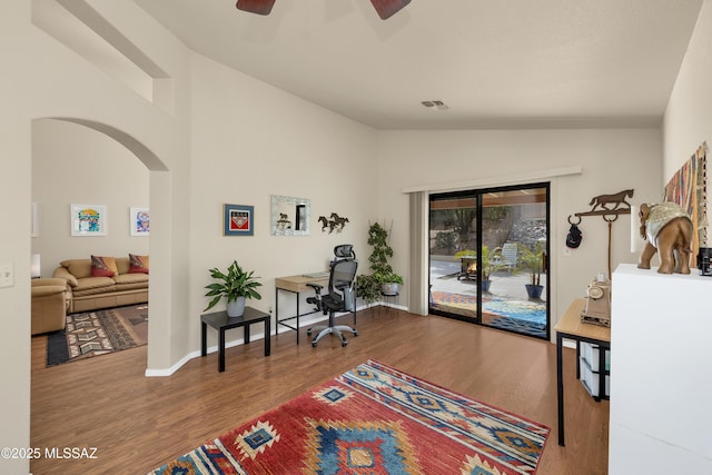 office area featuring arched walkways, wood finished floors, lofted ceiling, and visible vents