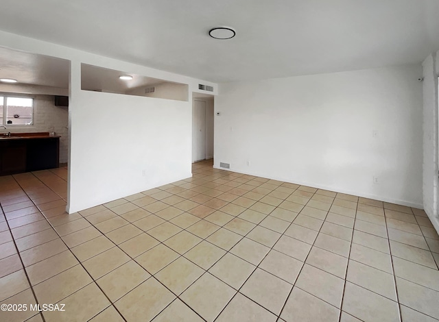 empty room featuring visible vents, a sink, and light tile patterned flooring