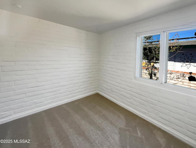 spare room with brick wall and baseboards