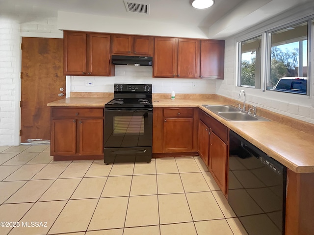 kitchen featuring light tile patterned floors, under cabinet range hood, a sink, visible vents, and black appliances