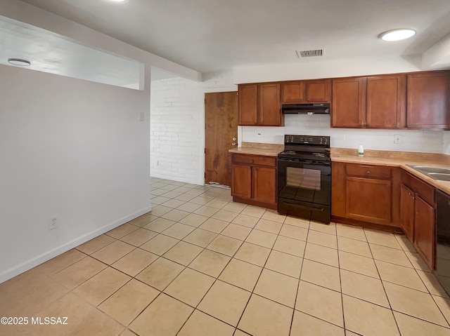 kitchen featuring brown cabinetry, light countertops, under cabinet range hood, and black / electric stove