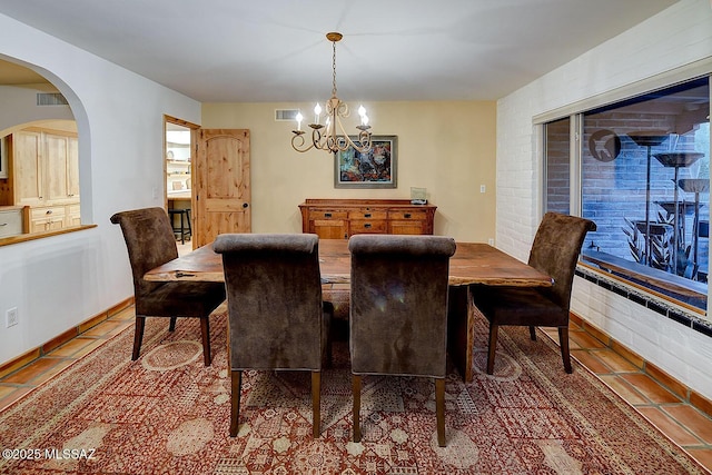 tiled dining room featuring a notable chandelier, arched walkways, and visible vents