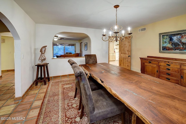 dining space featuring light tile patterned flooring, a chandelier, baseboards, visible vents, and arched walkways