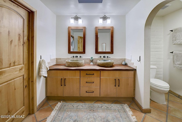 bathroom featuring toilet, double vanity, tile patterned floors, and visible vents