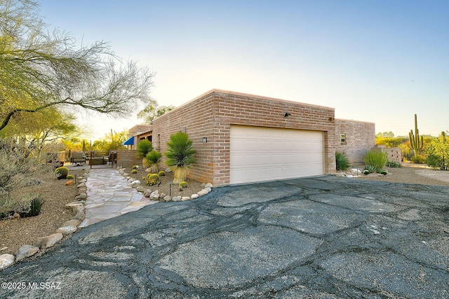 view of home's exterior featuring driveway, brick siding, and a garage