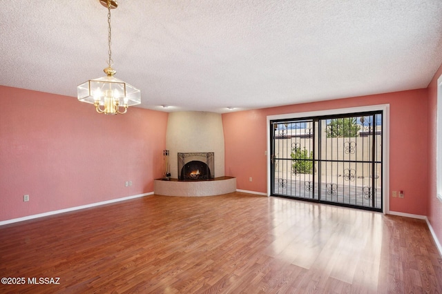 unfurnished living room with a textured ceiling, a fireplace, and wood finished floors