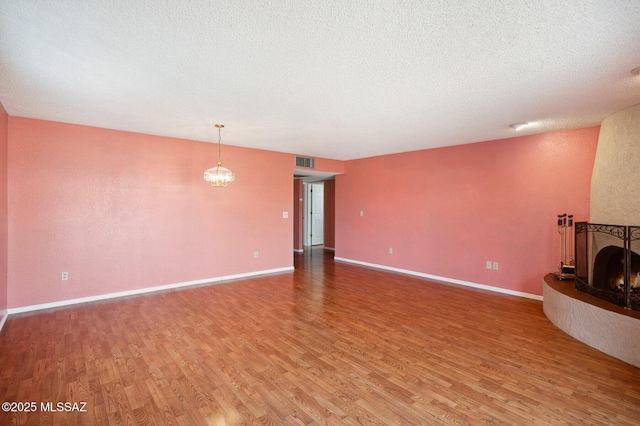 unfurnished living room featuring light wood-style floors, a lit fireplace, visible vents, and baseboards